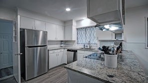A modern kitchen with white cabinets, stainless steel appliances, and granite countertops. - 7BR Workforce Stay Near I-55 & I-220 (Jackson)