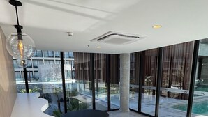 Ein modernes Interieur mit einer gebogenen weißen Theke, schwarzen Sitzgelegenheiten, großen Fenstern und Blick auf einen Pool.