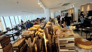 Ein moderner Essbereich mit Holzbrotpräsentationen, gestapelten Tellern und einem aufgeräumten, großzügigen Design.