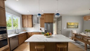 Una cocina moderna con armarios de madera, una isla de mármol y un cuenco de frutas.