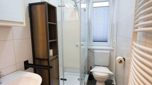 Une salle de bain compacte avec une douche à parois de verre, des toilettes et un lavabo avec un meuble en bois.