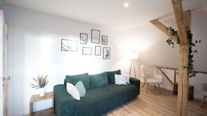 Una sala de estar moderna con un sofá verde, una mesa de centro de madera, una lámpara blanca y obras de arte enmarcadas en la pared.