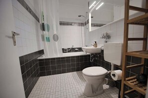 Ein modernes Badezimmer mit Toilette, Badewanne, Waschbecken und Dusche.
