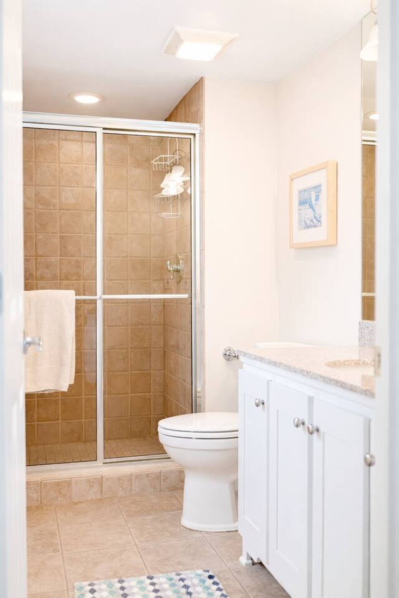 Een badkamer met een douchecabine van glas, een toilet en een witte wastafel met spiegel.
