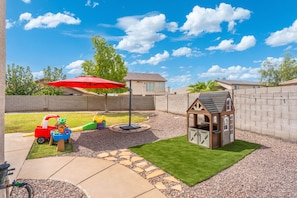 A backyard with a play area, a swing set, and a small wooden playhouse. - Desert Family Oasis, Pool, Spa & Kids’ Paradise (Avondale)
