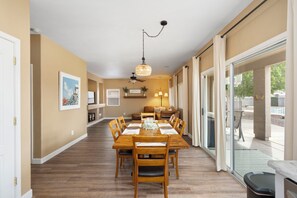 A dining area with a wooden table and chairs, a ceiling fan, and a view through large sliding glass doors. - Desert Family Oasis, Pool, Spa & Kids’ Paradise (Avondale)