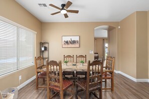 A dining room with a wooden table and chairs, a ceiling fan, and a framed picture on the wall. - Desert Family Oasis, Pool, Spa & Kids’ Paradise (Avondale)