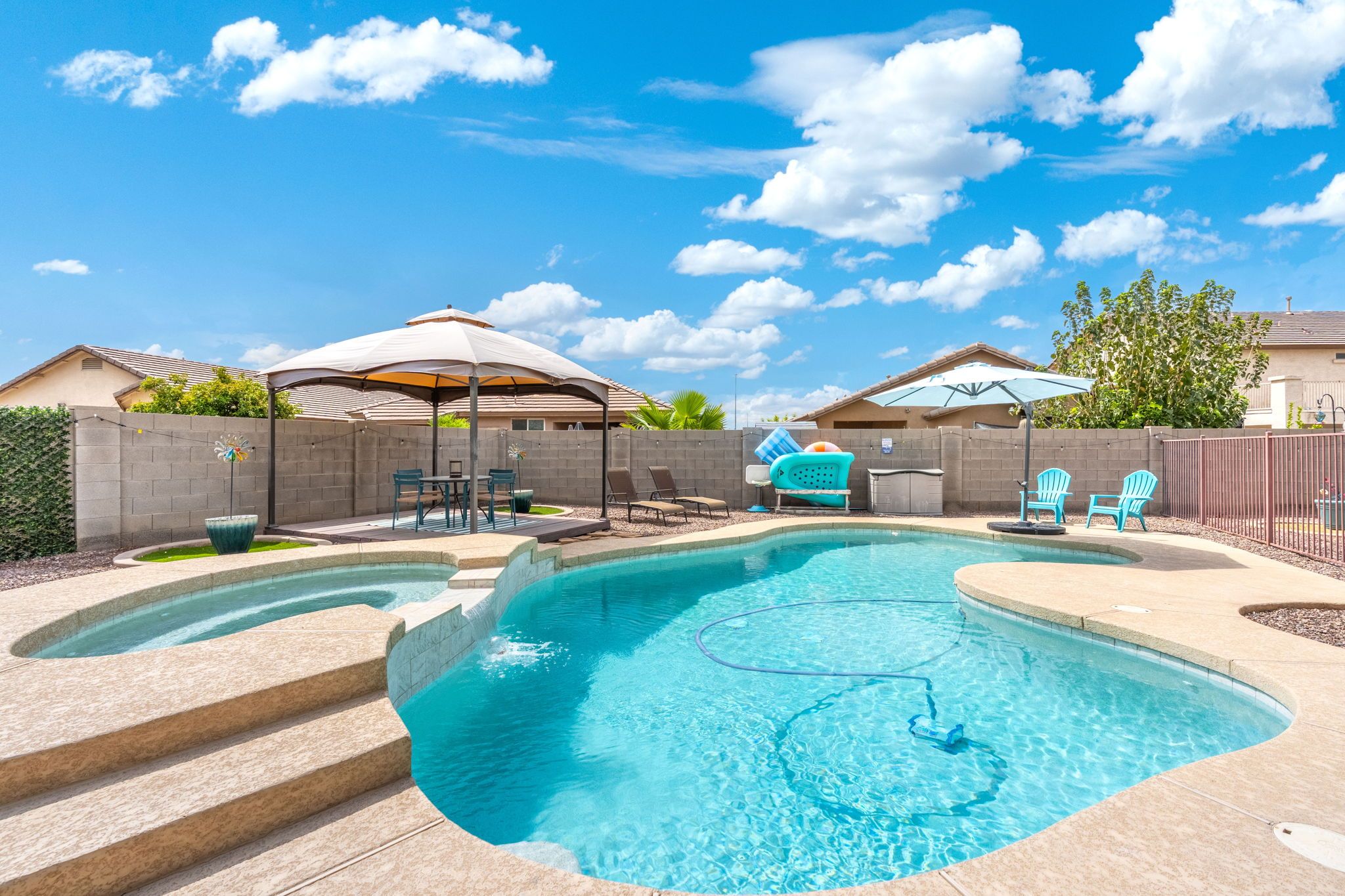 Un jardin avec une piscine, un espace salon extérieur et une terrasse couverte.