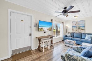 A living room with a television, a ceiling fan, a sofa, and a wooden coffee table. - 🌴Great for Large Groups | Cozy Outdoor Space | Linda's Cozy Collection🏖️ (Panama City Beach)