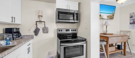 A compact kitchen with a microwave, oven, and coffee maker.