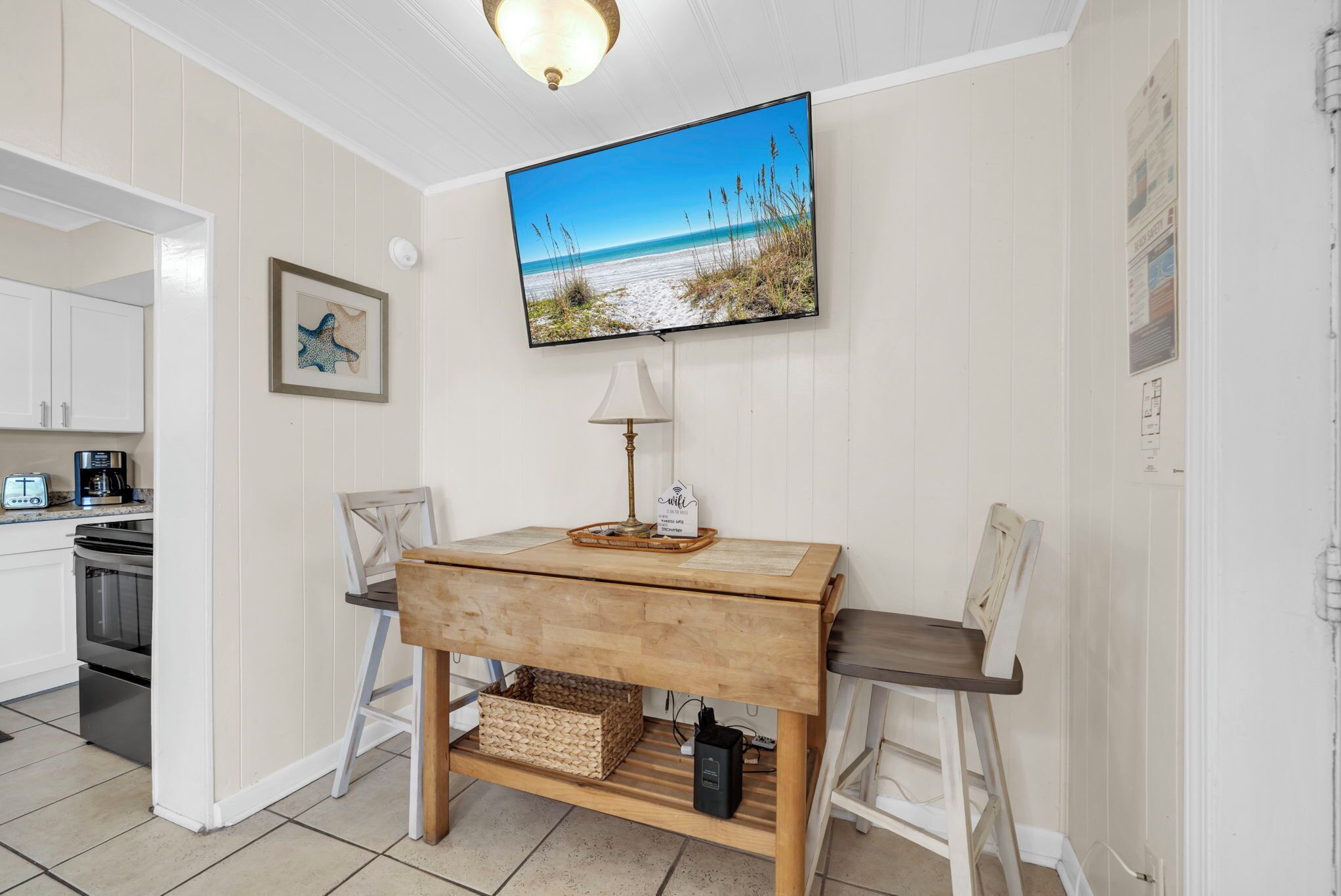 A kitchen with a wooden table, chairs, a television, and a framed picture on the wall.