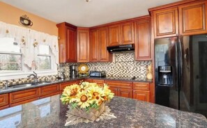 A kitchen with wooden cabinets, a granite countertop, a refrigerator, and a coffee maker. -  FIFA WORLD CUP 2026 , BEAUTIFUL 4 br. HOUSE RENTAL  in  CLIFTON NJ. (Clifton)