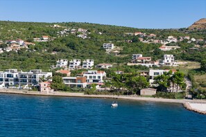 Eine Küstenstadt mit modernen Gebäuden, blauem Meer und hügeliger Landschaft.