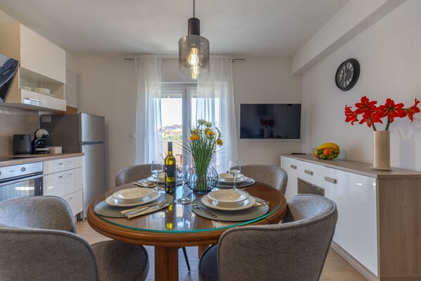 Una cucina moderna con zona pranzo, televisione e orologio a parete.