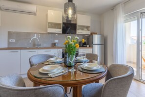 Una cucina moderna con mobili bianchi, forno integrato e zona pranzo con tavolo in vetro per quattro persone.