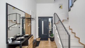 A modern hallway with a staircase, a wooden bench, a black table with plates, and a door with a mirror. - Villa Flokica with Heated Pool (Maslenica)