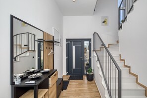 A modern hallway with a staircase, a wooden bench, a black table with plates, and a door with a mirror. - Villa Flokica with Heated Pool (Maslenica)