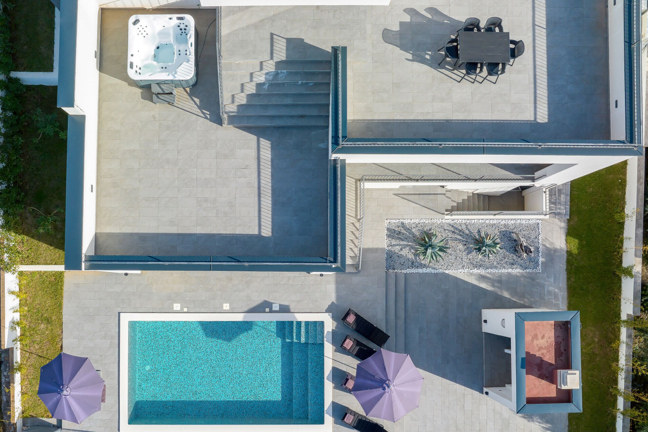 An aerial view of a modern hotel with a swimming pool, hot tub, and outdoor seating area.
