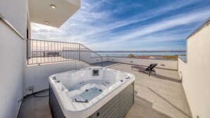 A rooftop terrace with a hot tub, outdoor seating, and a view of the sea. - Villa Flokica with Heated Pool (Maslenica)