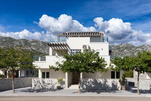 A modern building with a flat roof, large windows, and a stone wall. - Villa Jimmy with Heated Pool (Starigrad)