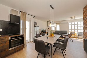 A modern kitchen with a built-in oven, a dining area with a table and chairs, and a living room with a sofa and chairs. - Villa Jimmy with Heated Pool (Starigrad)