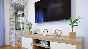 A living room with a TV, wooden cabinet, and decorative items. - Apartment Pavao with Whirlpool (Rovanjska)