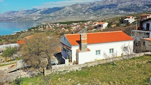 A coastal village with white houses, a clear blue sky, and mountains in the background. - Apartment Pavao with Whirlpool (Rovanjska)