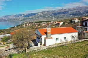 Ein Küstendorf mit weißen Häusern, blauem Himmel und Bergen im Hintergrund.