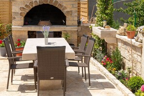 Eine Terrasse im Freien mit einem Steinkamin, Korbmöbeln und einem Blumentopf.