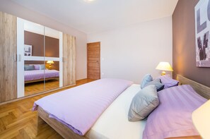 Una camera da letto con un letto, un armadio, uno specchio e una lampada a parete.