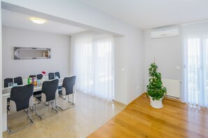 Ein modernes Wohnzimmer mit Essbereich, einer Topfpflanze und einer Klimaanlage.