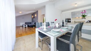 A modern dining area with a glass table, grey chairs, and a white ceiling. - Apartment Goga 2 with Shared Pool (Zadar)