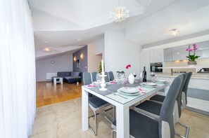 A modern dining area with a glass table, grey chairs, and a white ceiling. - Apartment Goga 2 with Shared Pool (Zadar)