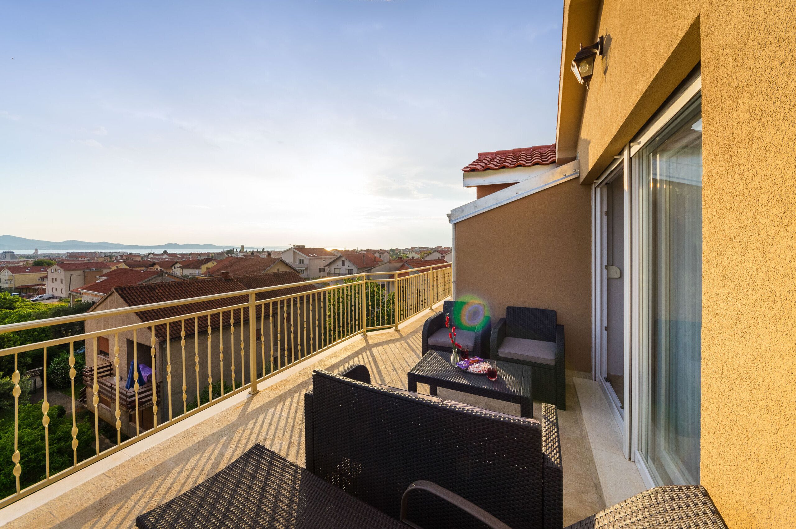 A balcony with a view of the city, a table with chairs, and a small table with a decorative item.