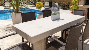 An outdoor dining area with a pool, wicker chairs, and potted plants. - Apartment Goga 2 with Shared Pool (Zadar)