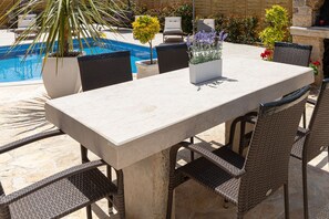 An outdoor dining area with a pool, wicker chairs, and potted plants. - Apartment Goga 2 with Shared Pool (Zadar)