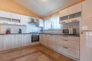 Eine moderne Küche mit hellen Holzschränken, einem Einbauofen, einer Mikrowelle und einem Kühlschrank.