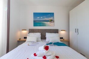 Ein Hotelzimmer mit einem Bett, einem Strandbild und einem Nachttisch mit einer Lampe.