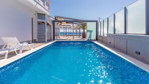 A swimming pool with clear blue water, white lounge chairs, and a view of the sea. - Apartment Paradiso No.4 with Sea View (Vir)
