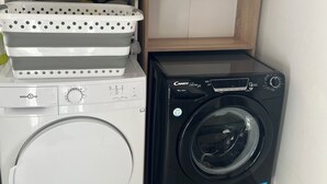 Un área de lavandería con lavadora y secadora de carga frontal, un gabinete blanco arriba y un gabinete de madera abajo.