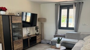 Una sala de estar moderna con sofá, televisor y un aparador.