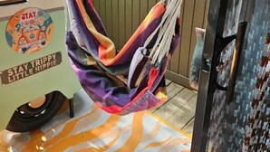 Eine Hängematte an einem Metallpfosten, eine farbenfrohe Matte am Boden und ein Fahrzeug mit dem Aufkleber 'Stay Trippy Little Hippie'.