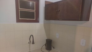 Eine kleine Küche mit Spüle, einem Fenster mit Jalousien und einem Schrank.