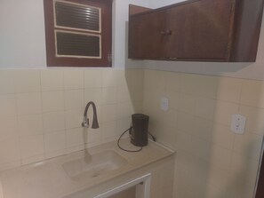 A small kitchen with a sink, a window with blinds, and a cabinet.