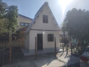 A small, single-story building with a pitched roof, a door, and two windows.