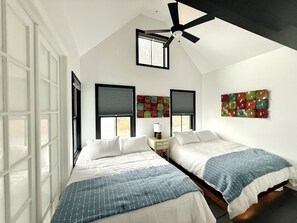 Un dormitorio con dos camas, un ventilador de techo y una ventana con persianas.
