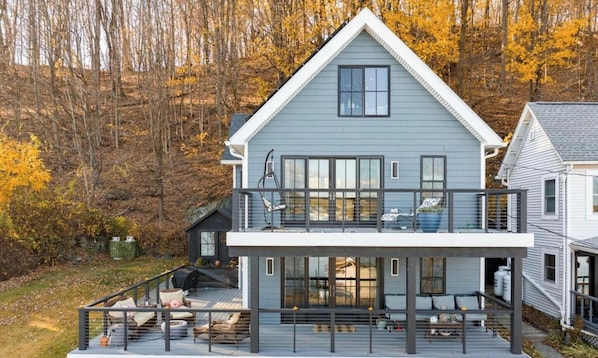 A two-story house with a balcony, a deck, and a large window.
