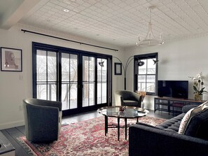 A modern living room with a sofa, armchair, glass coffee table, and a flat-screen TV.