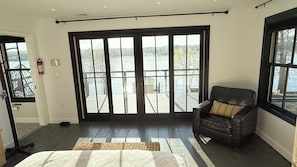 A room with a large window overlooking a dock, a leather chair with a patterned cushion, and a wooden floor.