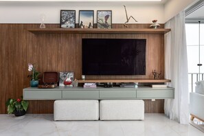 A modern living room with a large flat-screen TV, wooden panel wall, and a minimalist design. - 3-Bedroom Apartment 400m from Ipanema Beach (Rio de Janeiro)